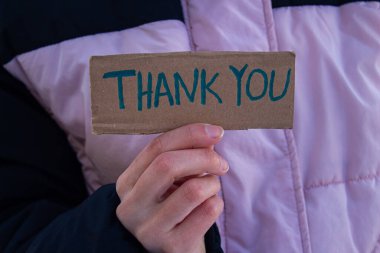 Elle tutulan karton kutuda teşekkür mesajı var. Bir iyilik ya da yardım için minnettar olmak. Kadın birine teşekkür ediyor..