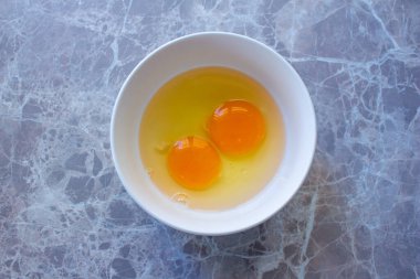 Mermer masada yumurta sarısı kabında çiğ yumurta sarısı, iki yumurta sarısının üst görüntüsü. Bir şeyler pişirmeye hazırlanıyorum.. 