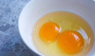 Tabakta çiğ yumurta sarısı, iki yumurta sarısı. Bir şeyler pişirmeye hazırlanıyorum.. 