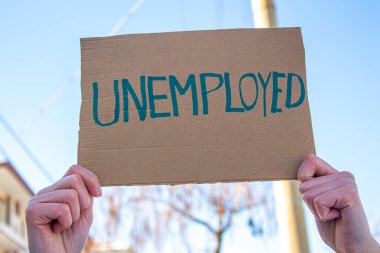 Üzerinde UNEMPLOYED yazan tabela tutan kadın. İşini kaybetme ve yeni bir iş arama kavramı. Finansal sorunları var ve bir işe ihtiyacı var..