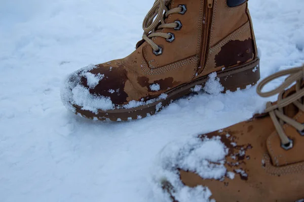 穿着棕色靴子站在雪地路上的女人 — 图库照片