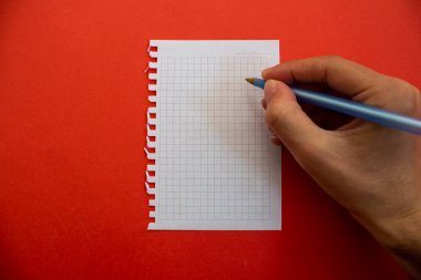 El ele tutuşup boş kağıda yazı yazmak. Kırmızı arkaplanda izole.