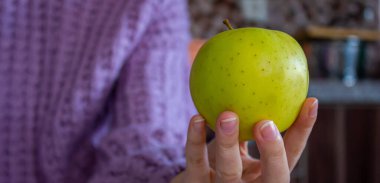 Elinde yeşil elma tutan bir kadının yakın plan fotoğrafı. Sağlıklı beslenme ve beslenme konsepti. Metin için boşluk.