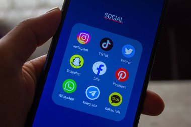 Sosyal medya uygulamaları (Instagram, TikTok, Twitter, Snapchat, Facebook, Pinterest, WhatsApp, Telegram, KakaoTalk) ekranda, akıllı telefonları elinde tutan simgeler. Afyonkarahisar, Türkiye - 4 Nisan 2022.
