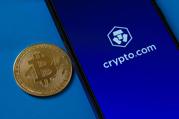 Логотип мобильного приложения Crypto.com на экране смартфона. Приложение для обмена криптовалют Crypto.com. Золотой биткойн. Афьонкарахисар, Турция - 6 апреля 2022 года.