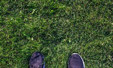 Çimlerin üzerinde bir çift ayakkabı. Fotokopi alanı olan yeşil çimlerin üzerinde duran adam.