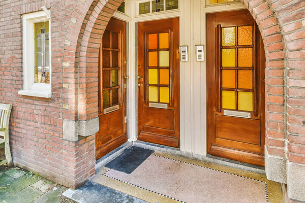 Wooden entrance doors with yellow glasses of a lovely brick residential building