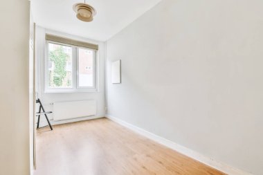 Küçük pencereli küçük, rahat bir oda.