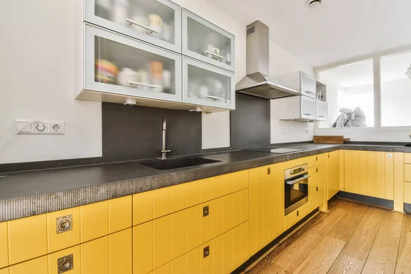 Schöne Küche mit gelber Küchenzeile und Hängeschränken — Stockfoto