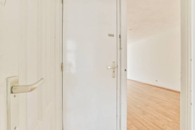 Parlak bir odada beyaz bir kapı.