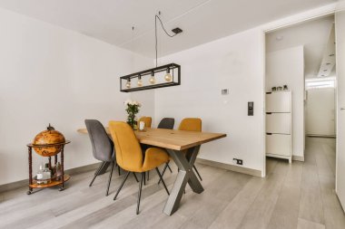 Ahşap masası ve sarı-siyah peluş sandalyeleri olan enfes bir yemek odası.