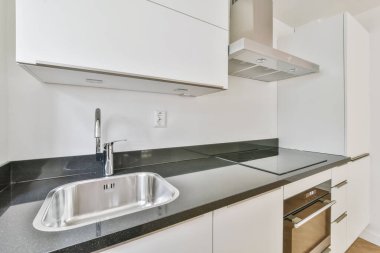 Siyah tezgahlı şık küçük bir mutfak.