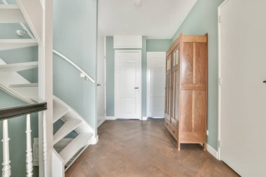 Yumuşak mavi duvarları ve sarmal merdivenleri olan şık bir salon.