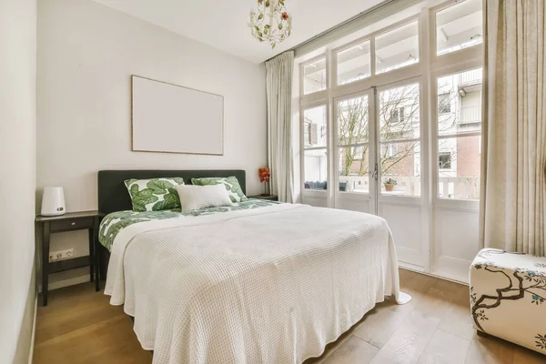 Entzückendes Schlafzimmer mit einem Bett, das mit einem Laken bedeckt ist — Stockfoto