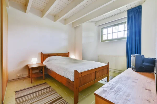 Um quarto atraente com uma cama de madeira e uma mesa de cabeceira — Fotografia de Stock