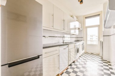 Siyah beyaz dama tahtası olan uzun bir mutfak.