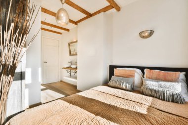 Yatağında bej bir ekose olan rahat bir yatak odası.