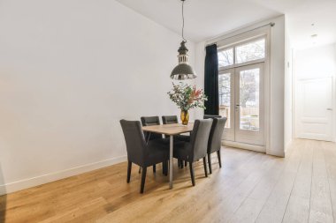 Masası ve siyah peluş sandalyeleri olan harika bir yemek salonu.