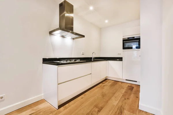 Una encantadora habitación con zona de cocina con encimera negra — Foto de Stock