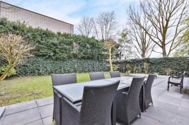 Hasır sandalyeler ve minimalist tarzda siyah bir masa.