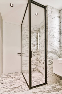 Duş kabini ve mermer duvarları olan çekici bir banyo.