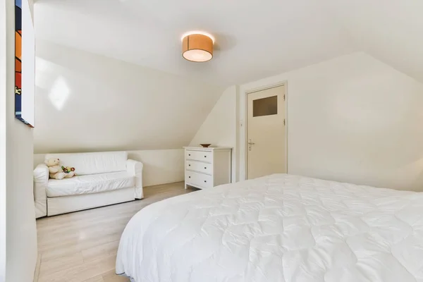 L'intérieur d'une belle chambre avec un lit doux recouvert d'une couverture blanche — Photo