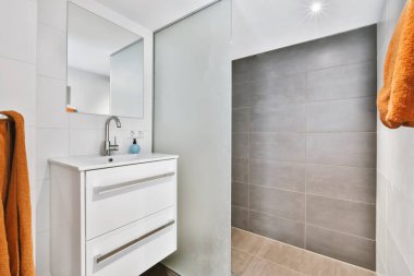 Banyo minimalist tarzda beyaz çekmeceleri var.