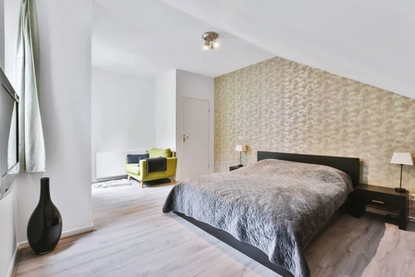 Acogedor dormitorio con una cama cubierta con una manta gris — Foto de Stock