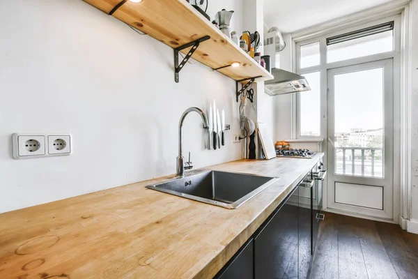 Хорошая кухня с черным кухонным набором и деревянной столешницей — стоковое фото