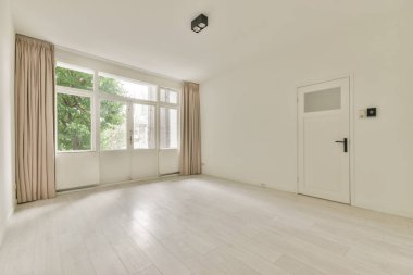 Geniş bir oda, büyük pencereleri ve kapısı var.