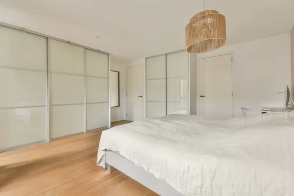 Una spaziosa camera da letto con un grande letto bianco — Foto Stock