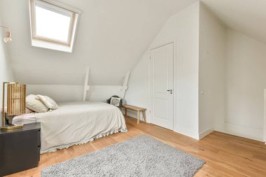 Pencereleri eğimli, rahat bir yatak odasının içi.