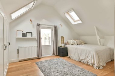 Pencereleri eğimli, rahat bir yatak odasının içi.