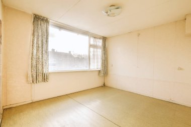 Parlak pencereli, ferah, boş bir odanın içi.