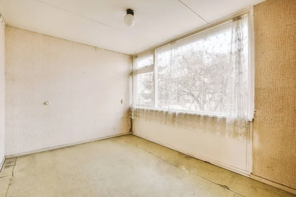 Parlak pencereli, ferah, boş bir odanın içi.
