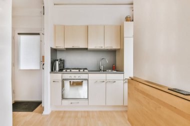 Bir sürü dolabı olan minimalist tarzda rahat bir mutfak.