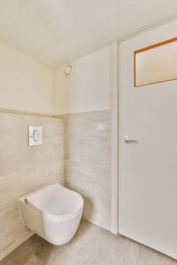 Menteşeli tuvaleti olan gri tonlu banyo.
