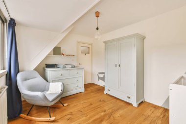 Bir sürü dolabı ve sallanan sandalyesi olan geniş bir oda.