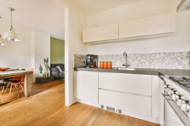 Beyaz mobilyalar ve mozaik fayanslarla dolu geniş bir mutfak.