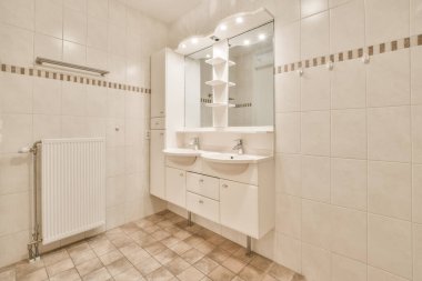 Banyo içi beyaz ve bej fayanslarla dolu.