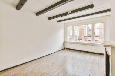 Geniş pencereli, boş bir oda.