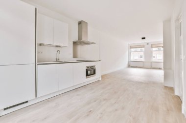 Geniş, boş, köşeli, aydınlık bir oda.