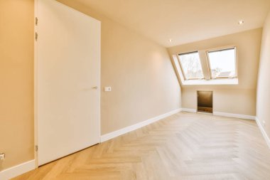 Modern bir evin parke zemininde pencereleri olan boş bir odanın genel manzarası.