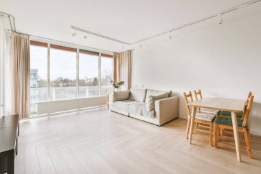 Televizyonsuz oturma odası, ama geniş panaromik pencereli ve oturma masalı.