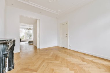 Büyük, boş, ferah, beyaz bir çatı katı odası ve yan odaya açılan bir kapı.