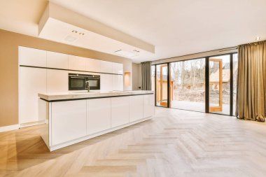 Beyaz tasarım ve arka bahçeye erişimi olan minimalist bir mutfak.