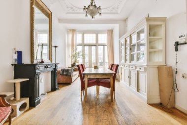 Oturma odasında büyük bir ayna, raf, masa ve benzeri şeyler var.