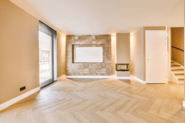 Geniş pencereli boş bir oda ve modern bir evin parke zemininde küçük bir şömine.