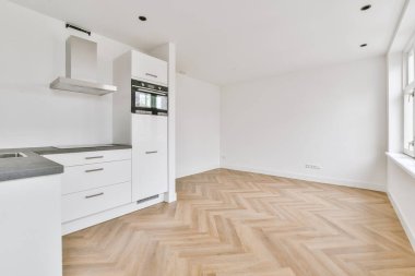 Beyaz duvarları, ahşap zemini ve boş odası olan modern mutfağın köşesi.