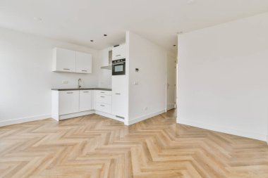 Beyaz duvarları, ahşap zemini ve beyaz dolapları olan modern mutfağın köşesi.